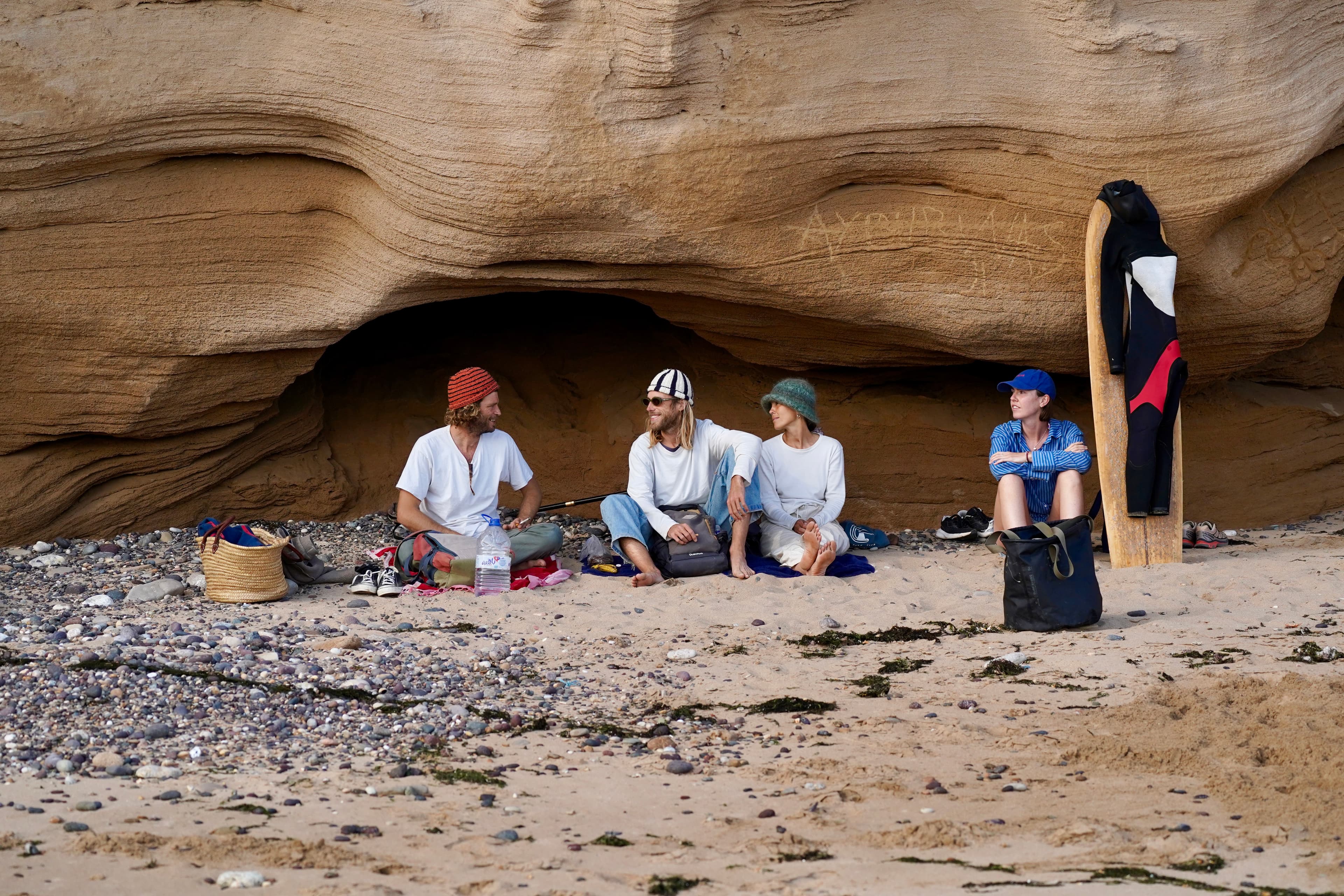 Friends gathered together under the rocks on the coast near Cap Sim, Morocco