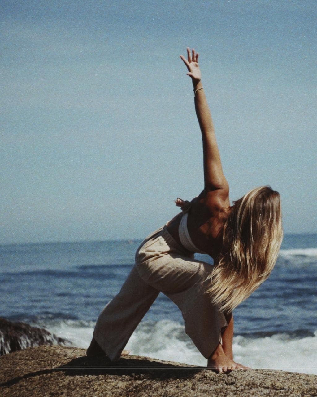 Karen Guez in a yoga pose on the rocks above the ocean